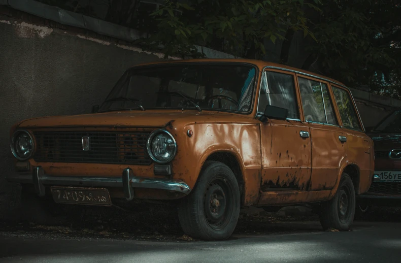 an old brown station wagon sitting on the side of a street