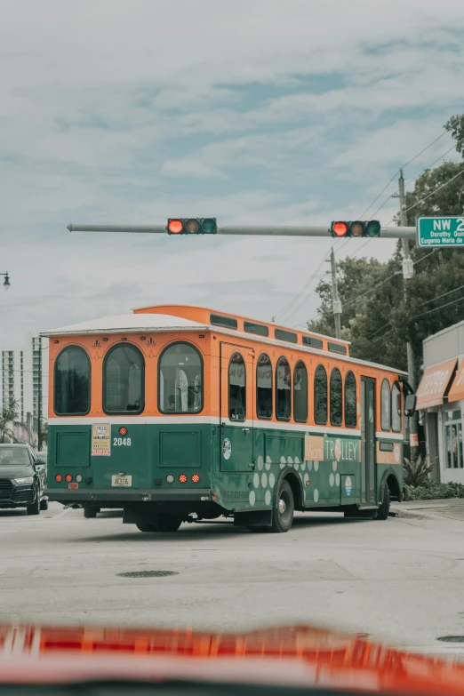 a small green and orange bus driving down the road