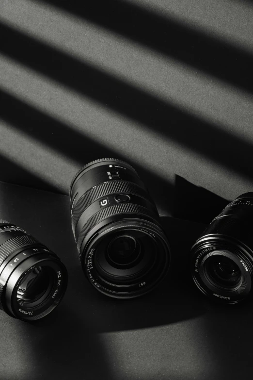 three cameras sitting on top of a desk next to a pen