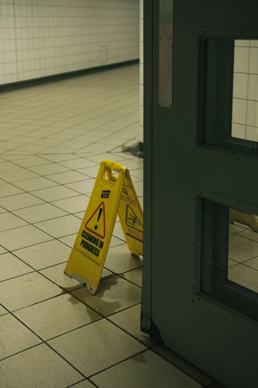 a yellow caution sign sitting on the floor next to an open door