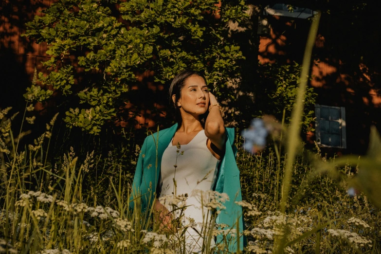 woman in a field with a blue jacket looking to her left and looking at the sky