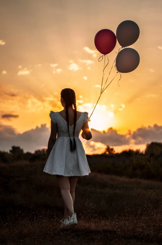 a woman standing with balloons flying above her