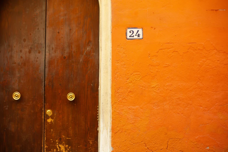 a wooden door in front of an orange wall with a number twenty four