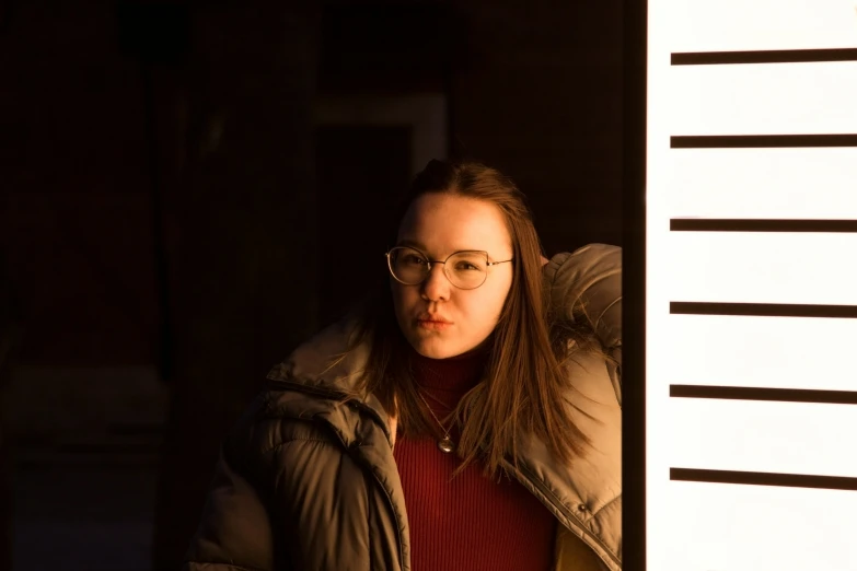 a woman standing next to a building wearing glasses