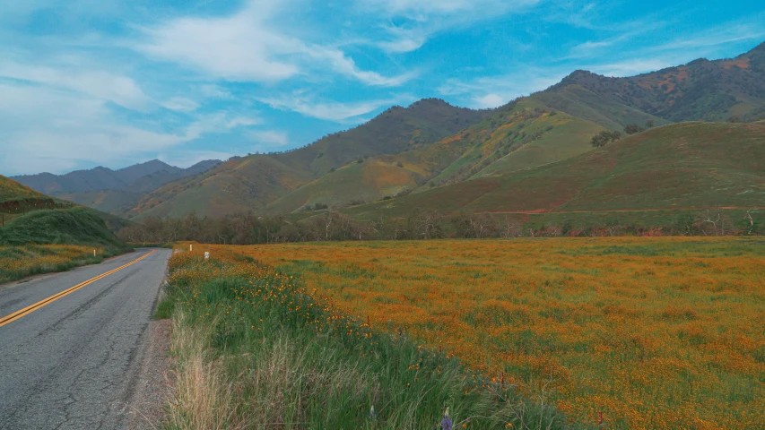 a long stretch of country road next to green mountains