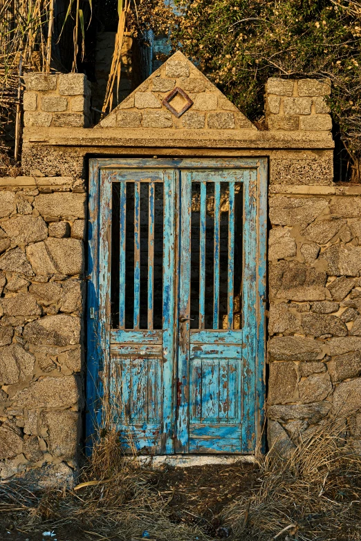 two wooden doors with bars and an old brick wall