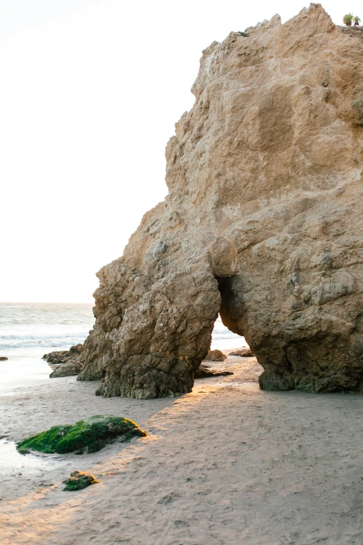 a rock formation sitting on top of a sandy beach