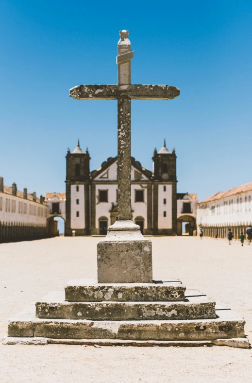 a large stone cross in front of a large building