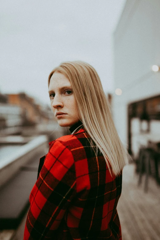 a woman standing on a pier looking back with a serious look