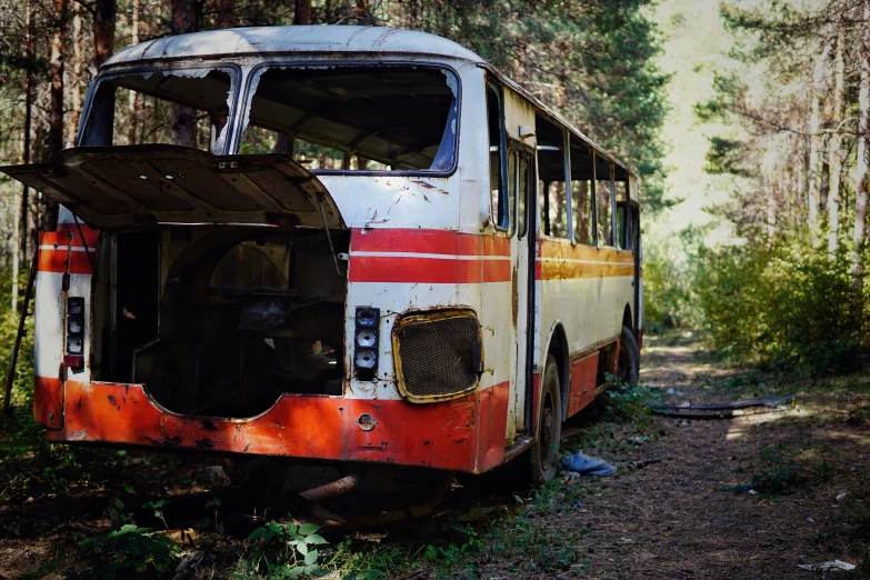 an old abandoned bus sits in the middle of a forest