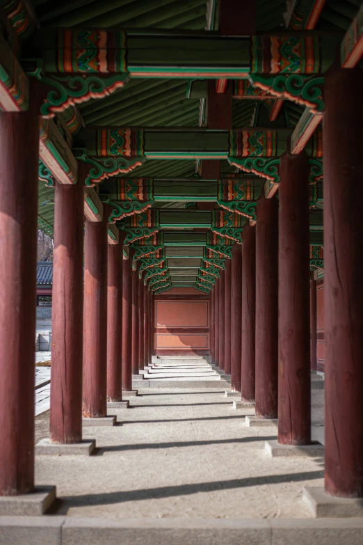 rows of red and green pillars in the middle of a walkway