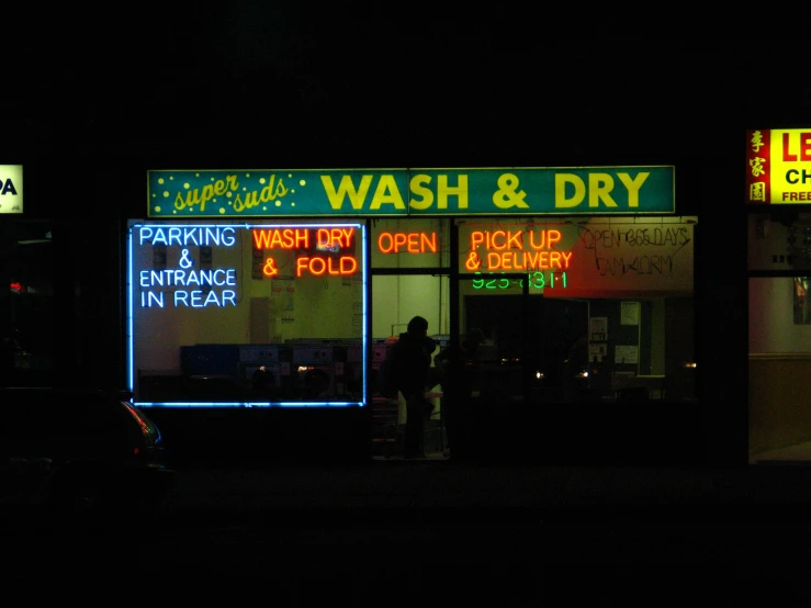 two men stand outside the store of car wash and dry