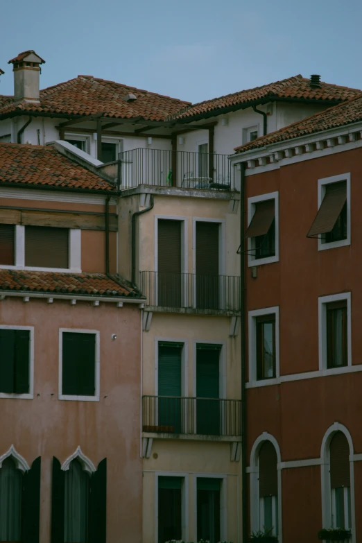 two different buildings with balconies, one has a clock on the roof