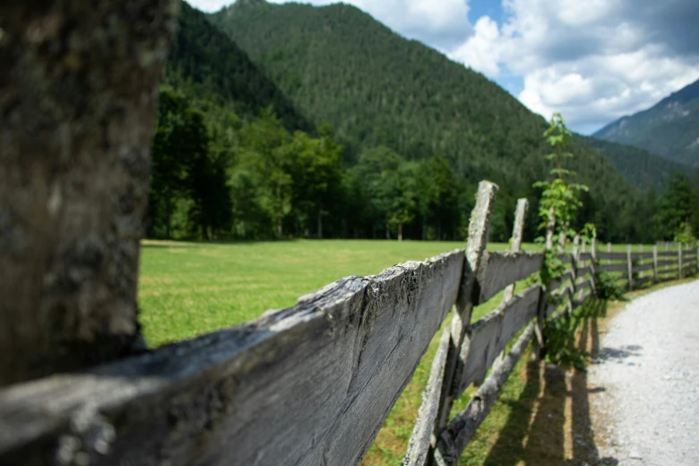 a wooden fence in the middle of a field and mountain