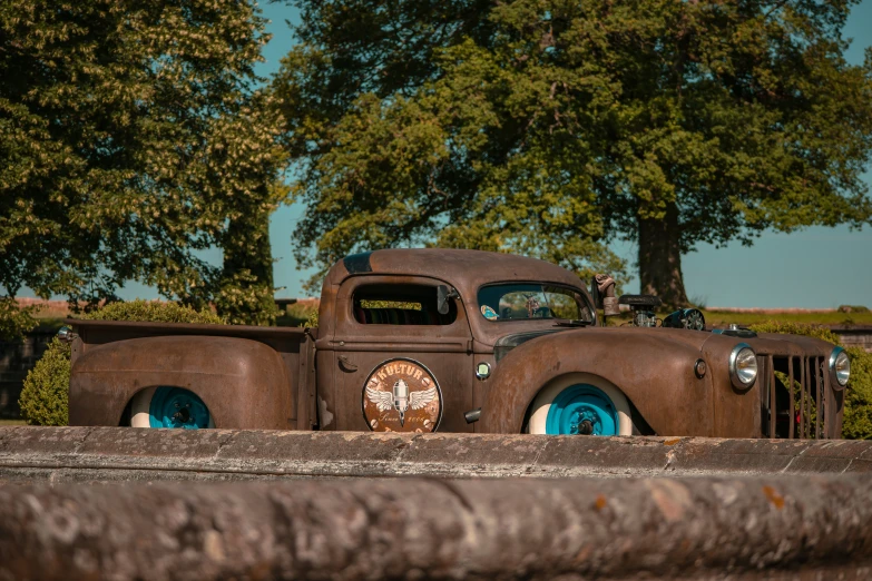 a rusty, old car parked in front of a tree