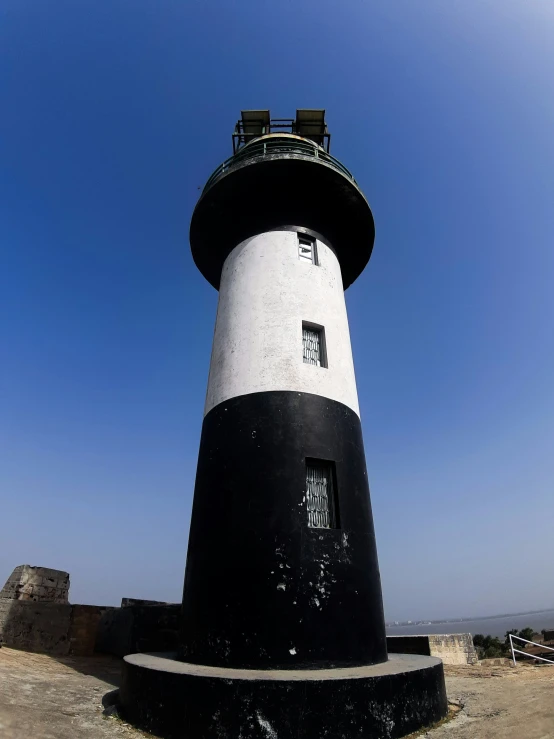 a black and white lighthouse with two chairs sitting on top of it