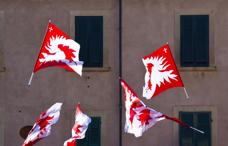 red and white flags are flying in front of a building