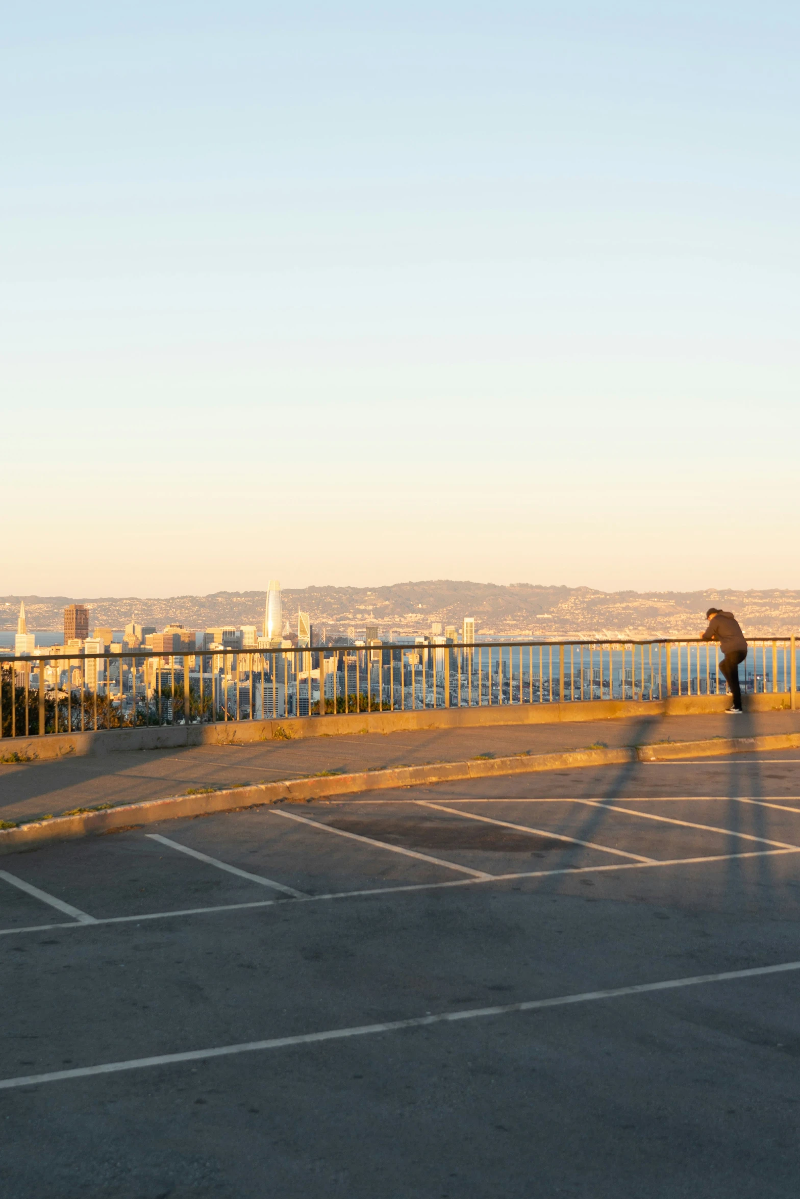 man walking in an empty parking lot towards the ocean