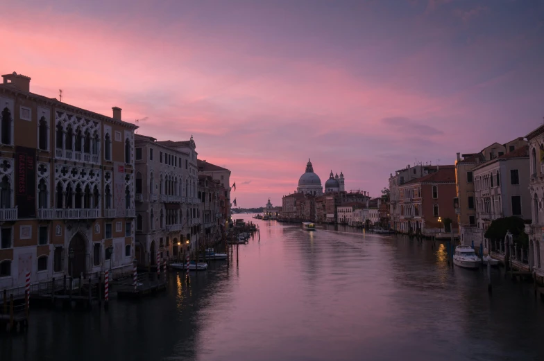 a waterway in venice, italy at dusk with some boats parked on it