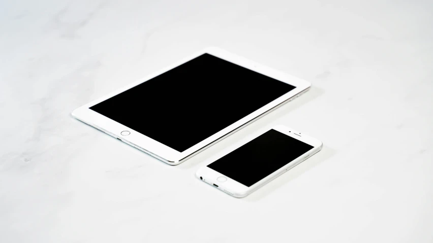 a tablet and mobile phone sitting side by side on a white table