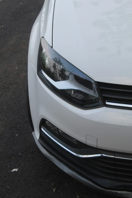 the front view of a white volkswagen sedan on pavement