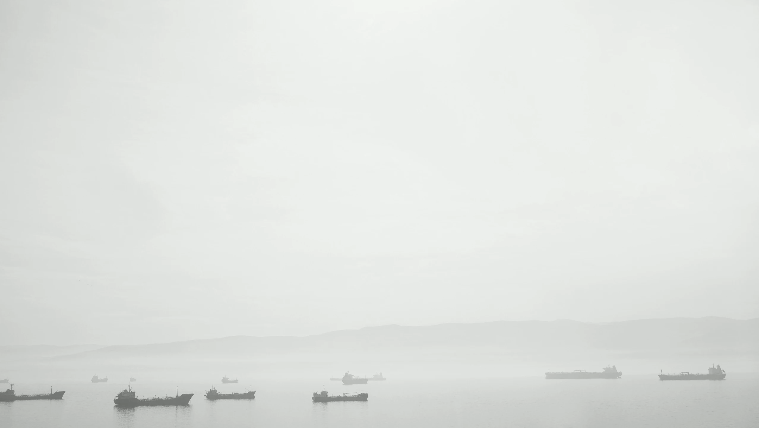 several ships floating on water on a foggy day