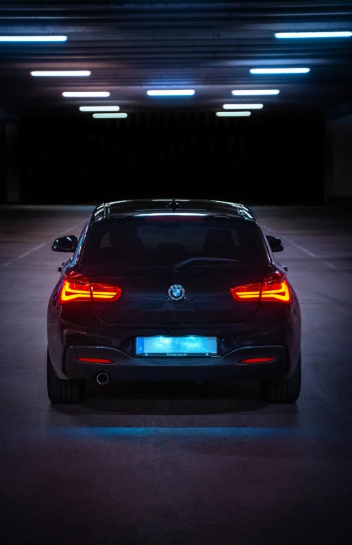 the rear end of a black car with the lights on