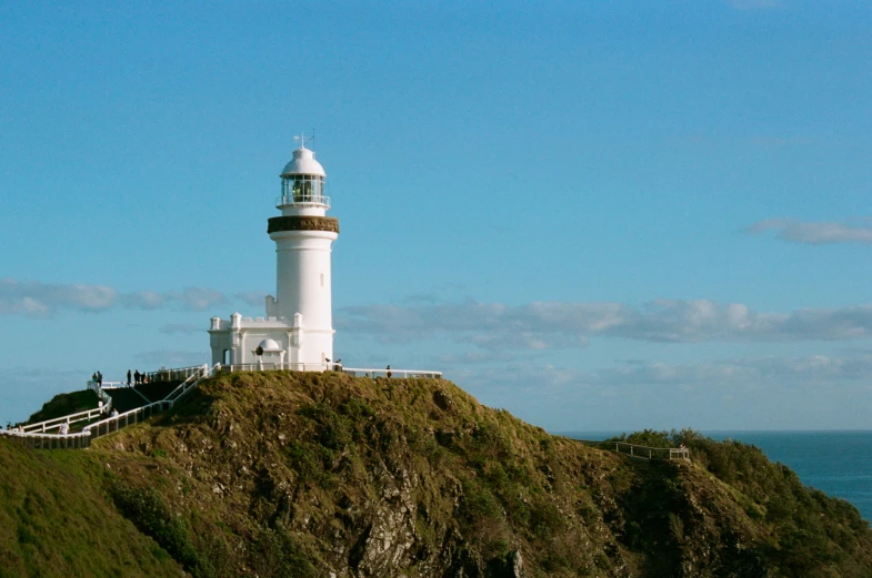 a white lighthouse on top of a hill by the ocean