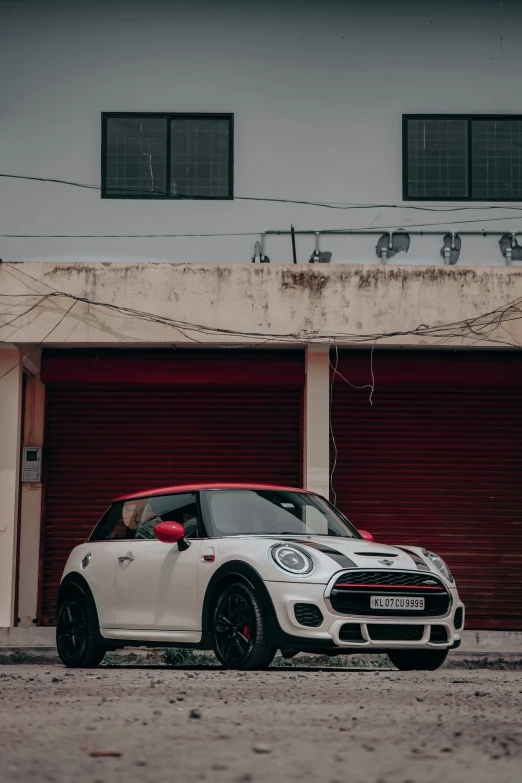 a white mini cooper parked in front of a red garage