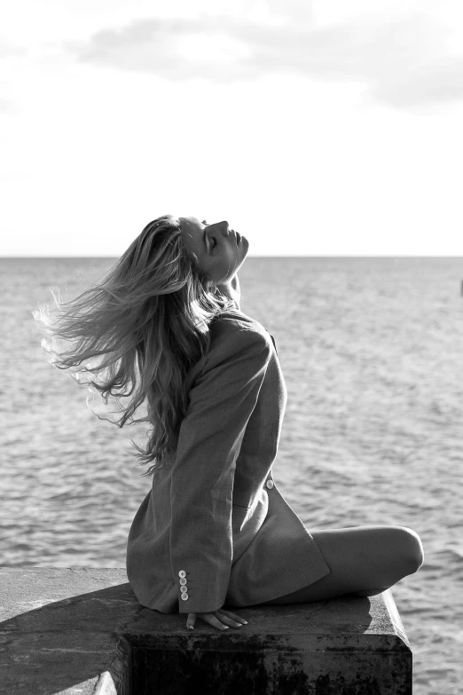 a woman is sitting on the edge of a pier