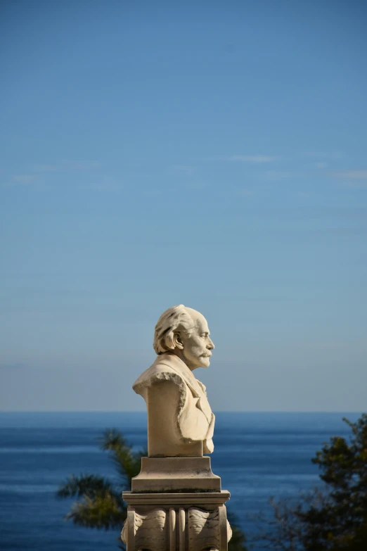 the statue sits on a pedestal in front of the ocean