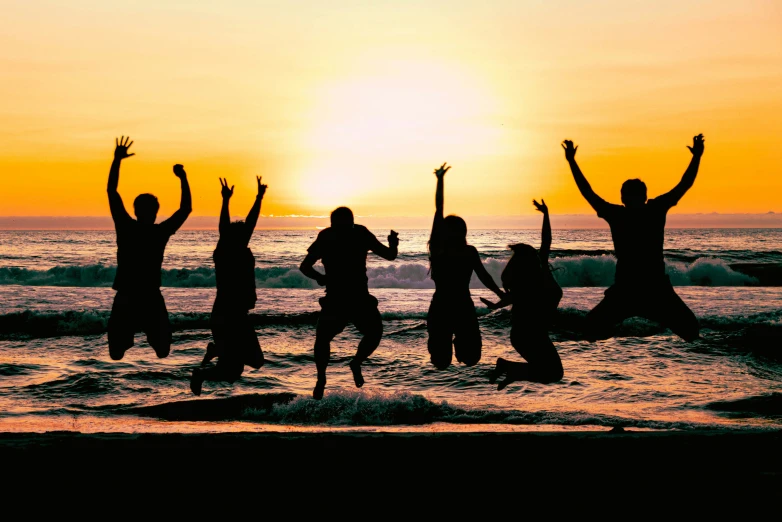 the people are jumping in the air near the ocean