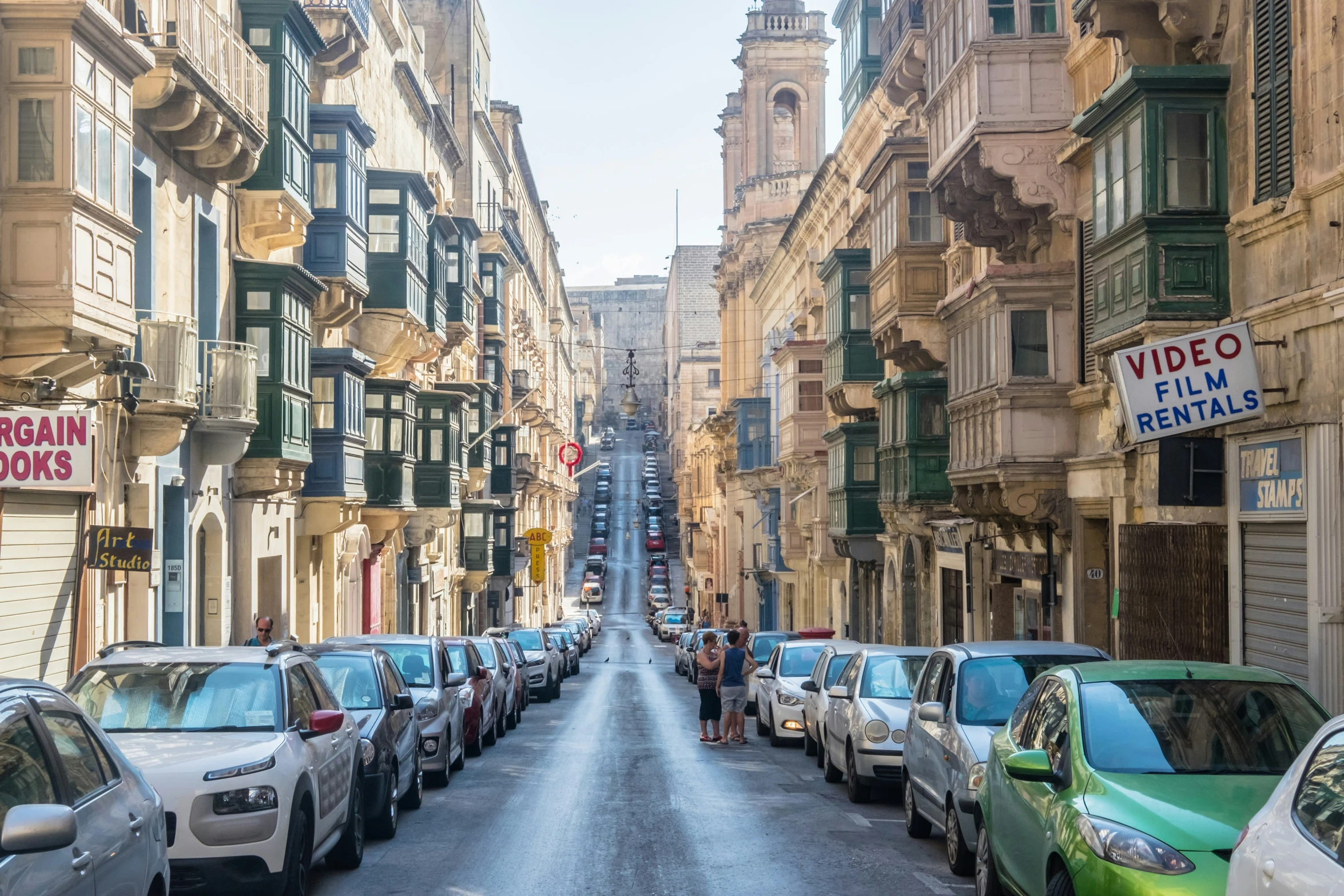 a narrow city street filled with parked cars