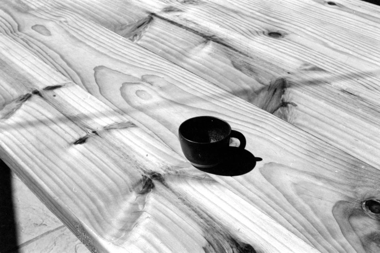 black and white image of a wooden table with a cup