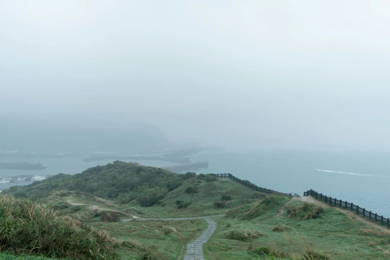 a walkway going uphill towards a hill next to the ocean