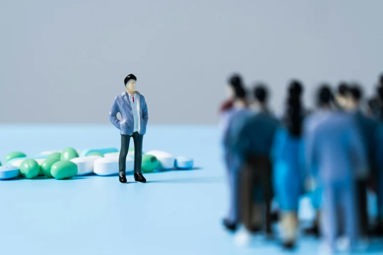 a miniature figurine is standing among several pills