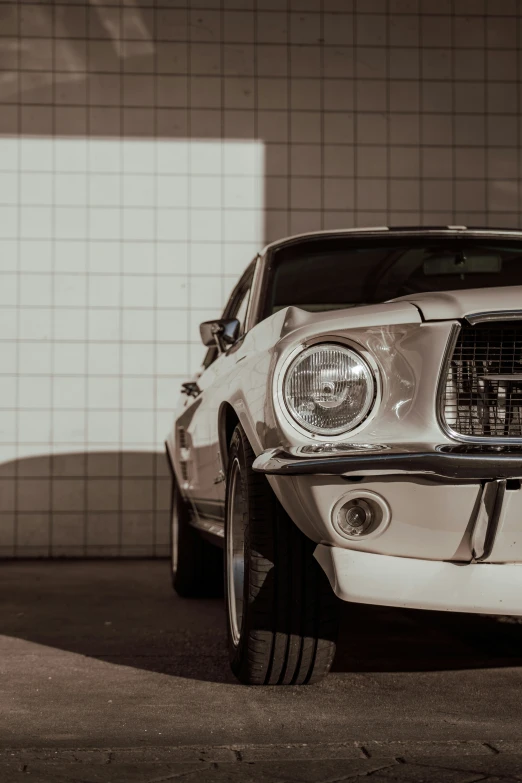 a white mustang parked in a garage next to a brick wall