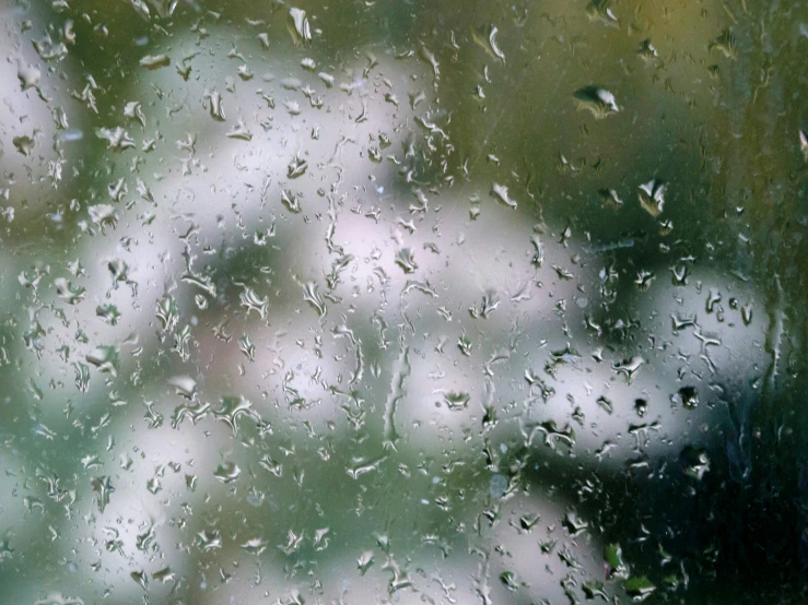 water droplets on a window with the outside of a house behind