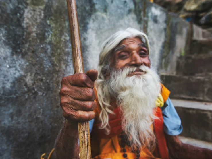 an old man holds a wooden stick in his hand