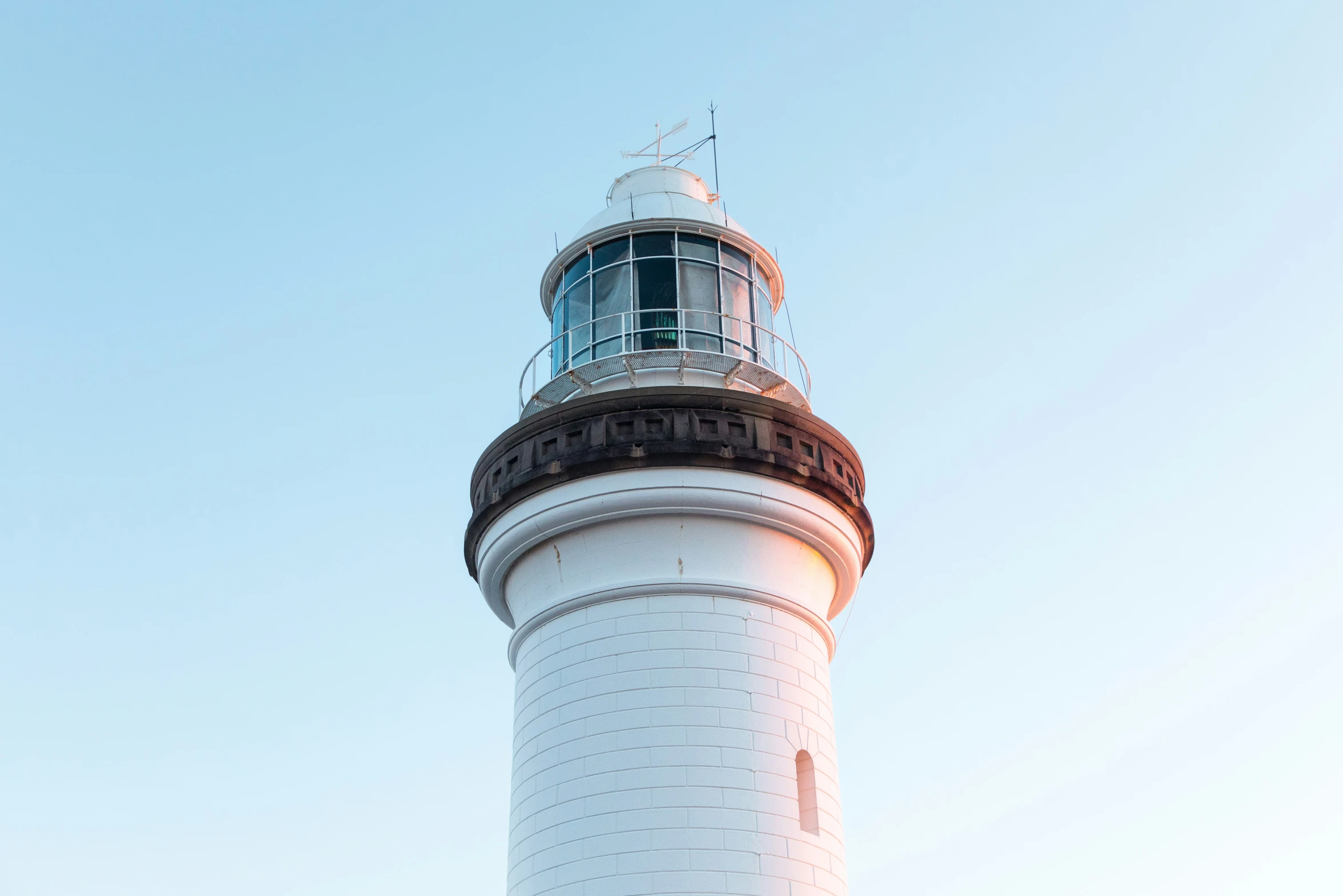 a tall white light house with a sky background