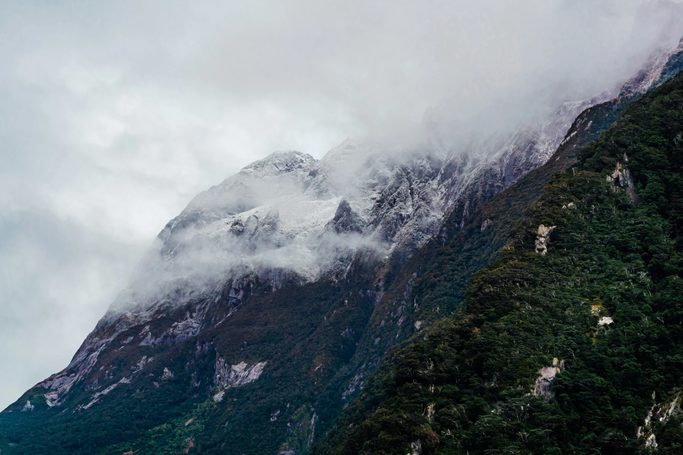 mountains covered with a snow capped top, with cloud hanging off the top