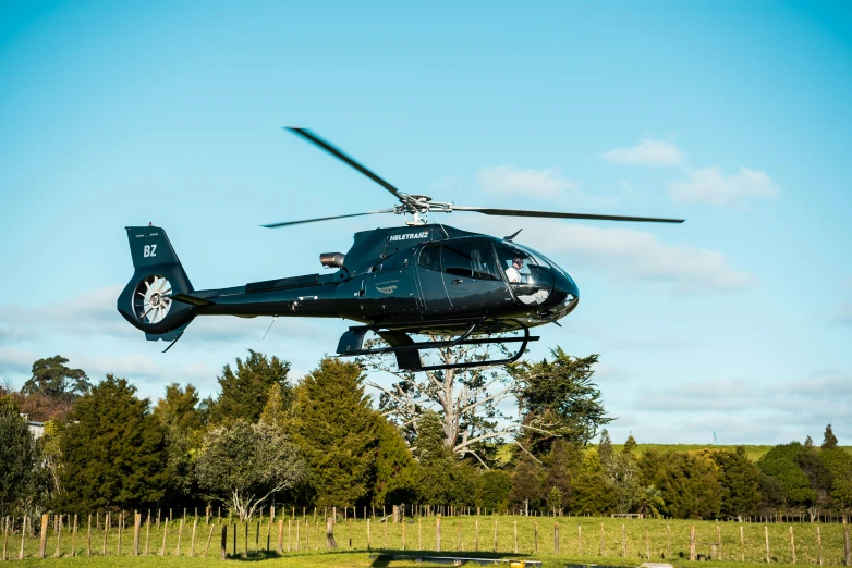 a helicopter is flying over a field of grass