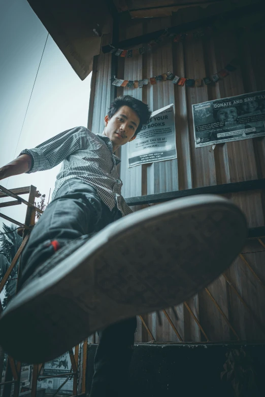 a young man with short hair and plaid shirt on a skateboard