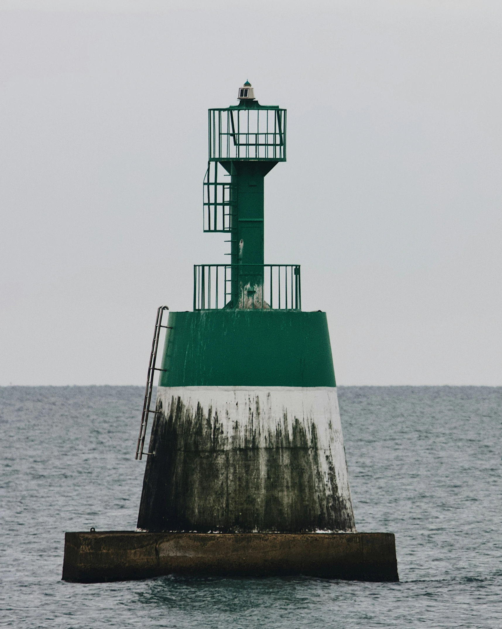 there is a large green and white light tower in the water