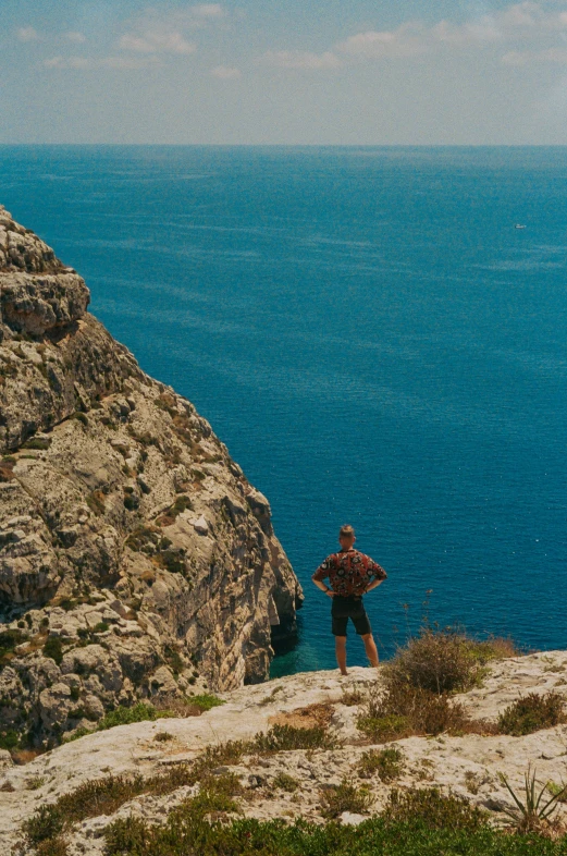 a person standing on top of a cliff looking out at the water