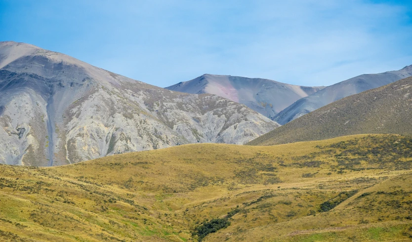 several mountains are shown with green grass and blue sky