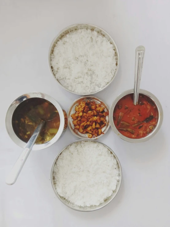 rice, currys and beans are placed in bowls on a white surface