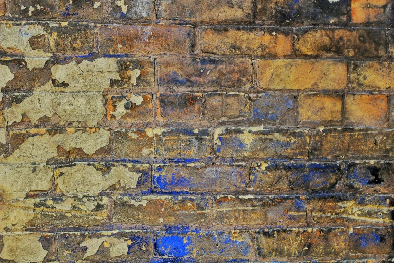 a rusted out brick wall with lots of blue and yellow paint