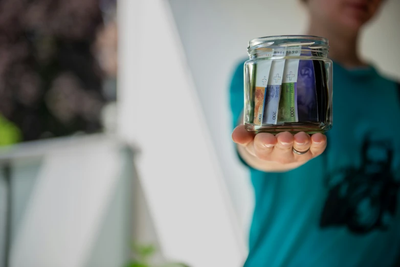 someone holding a jar full of colored items in their hands