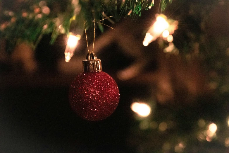 a red ornament hangs from a christmas tree